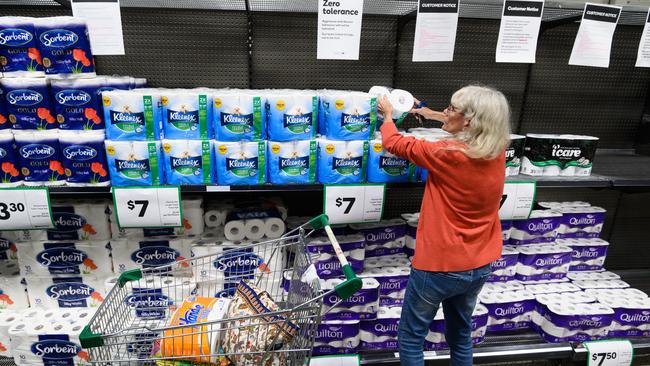 A woman picks up a packet of toilet paper in a Woolworths Supermarket in Marrickville. Picture: AAP/ James Gourley.