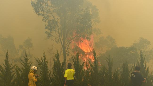 Workers battle in thick smoke to put out a bushfire near West Queanbeyan. Picture: AAP.