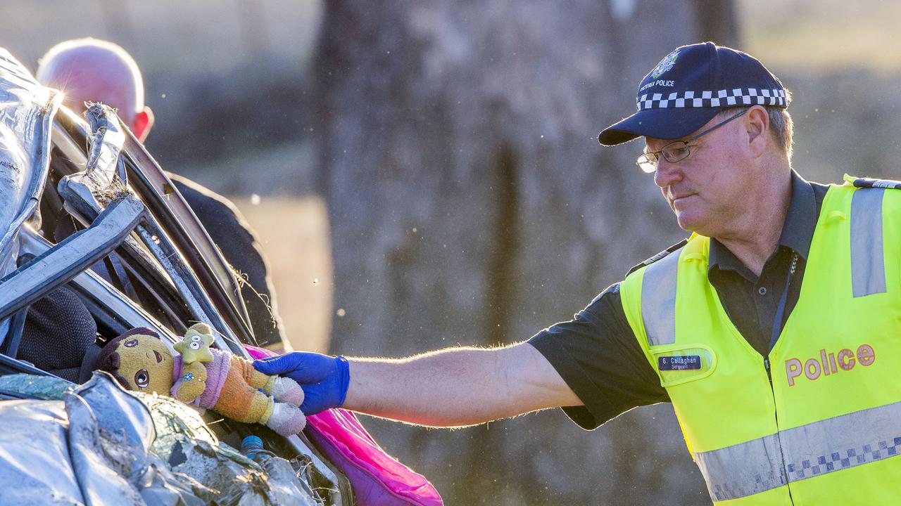 Car accident on Goulburn Valley Highway East of Yea. 4WD rolls 80 meters into paddock with one female adult and three children. A police officer picks up a dora the explorer teddy that was thrown from the car during the accident. Picture: Jason Edwards