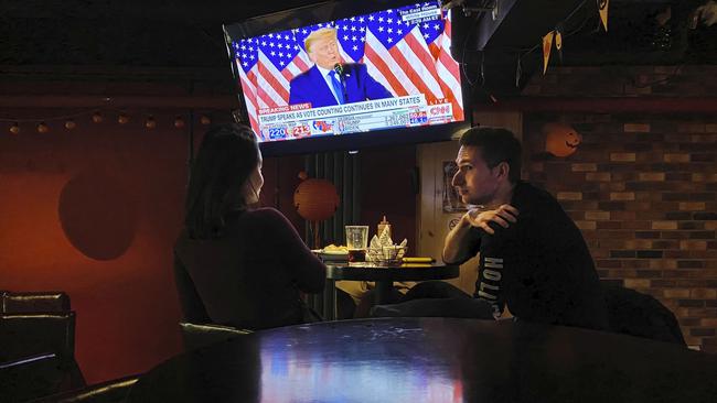 Customers at a local bar in Beijing, China watch a speech by U.S. President Donald Trump on a television. Picture: Getty Images