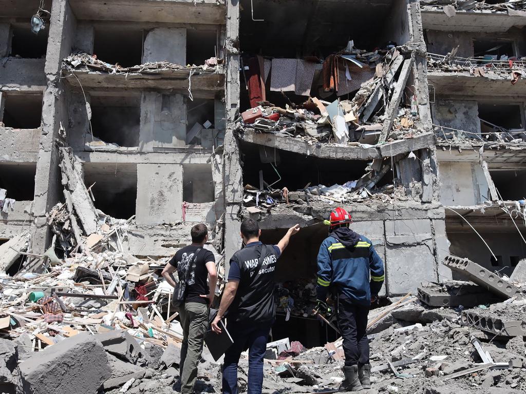 A war crimes prosecutor (centre) and a rescuer (right) and a civil, look at a destroyed building after being hit by a missile strike in the Ukrainian town of Sergiyvka. Picture: Oleksandr Gimanov / AFP