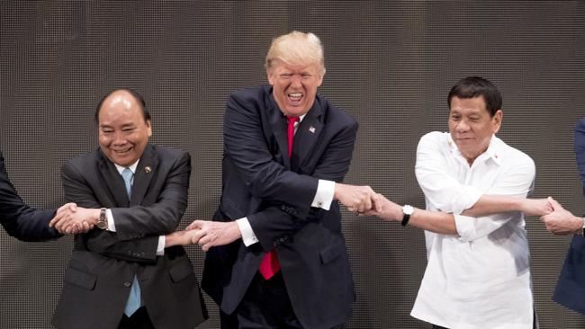 FILE  - In this Nov. 13, 2017, file photo, U.S. President Donald Trump, center, reacts as he does the "ASEAN-way handshake" with Vietnamese Prime Minister Nguyen Xuan Phuc, left, and Philippine President Rodrigo Duterte on stage during the opening ceremony at the ASEAN Summit at the Cultural Center of the Philippines in Manila, Philippines. Trump has proven himself an unconventional leader time and time again in his first year in office. (AP Photo/Andrew Harnik, File)