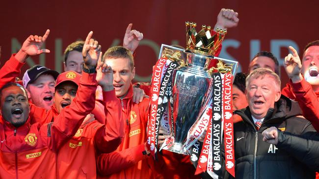 Retiring iconic Manchester United manager Alex Ferguson (R) and his players hold the Premier League trophy outside the town hall in Manchester, north west England, on May 13, 2013 during the team's victory parade to celebrate winning the Premier League for the 13th time.