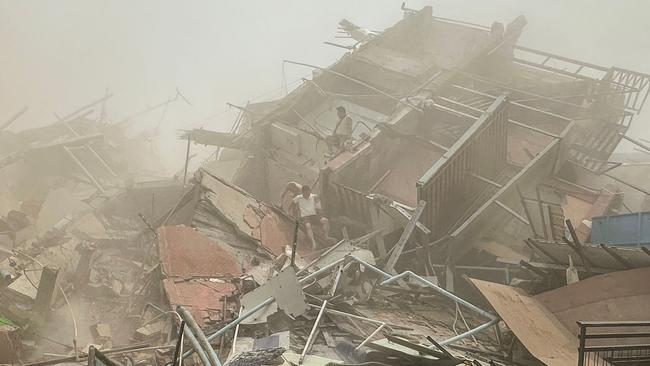 People inspect the debris of a collapsed building. Picture: AFP