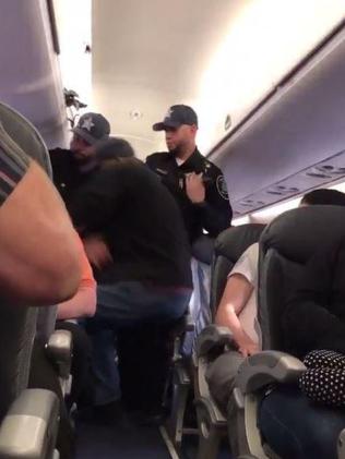 Police grab the man from his seat. Picture: Twitter