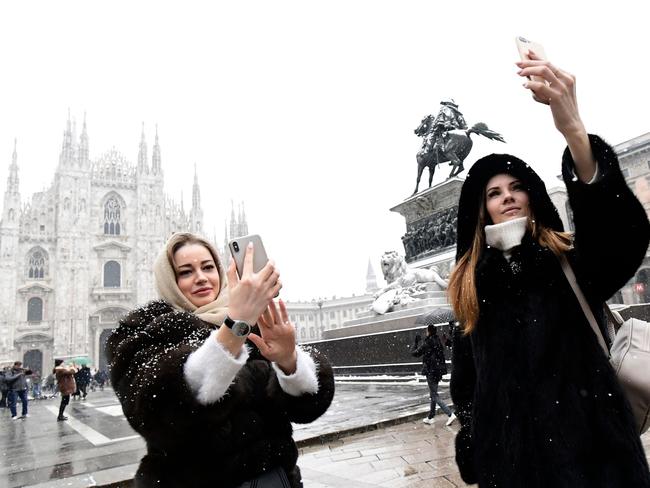 Tourists make a selfie with their cellphones at Duomo square after snowfall in Milan on March 1, 2018. Fresh heavy snowfalls and icy blizzards were expected to lash Europe on March 1 as the region shivers in a deadly deep-freeze that has gripped countries from the far north to the Mediterranean south. Picture: AFP