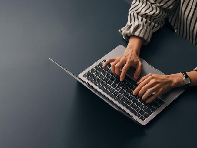 A from above view of an unrecognizable Caucasian copywriter typing on her laptop while sitting at her office desk. (copy space)