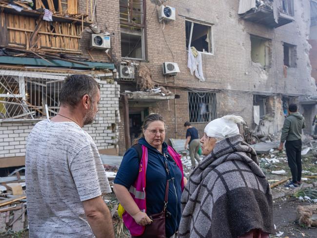 A volunteer listening to local residents, including an injured woman, next to a destroyed residential building following a missile attack in Zaporizhzhia. Picture: Handout / Zaporizhzhia Regional Military Administration / AFP