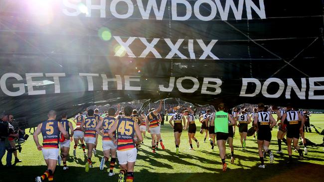 Port and Crows players run on to the field under a joint banner, in tribute to Phil Walsh, for Showdown 39. Pic: Calum Robertson