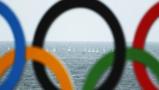 The Women's Laser Radial races are seen through the beachside Olympic rings at the Marina da Gloria in Rio.