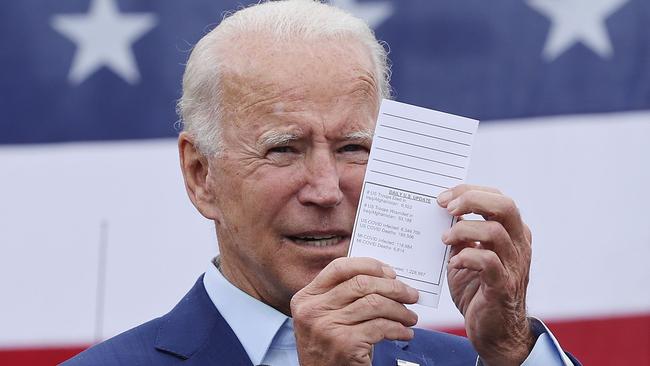 Joe Biden holds up his schedule with the latest numbers of people who have died from the coronavirus while addressing union members outside the United Auto Workers Region 1 offices. Picture: AFP.