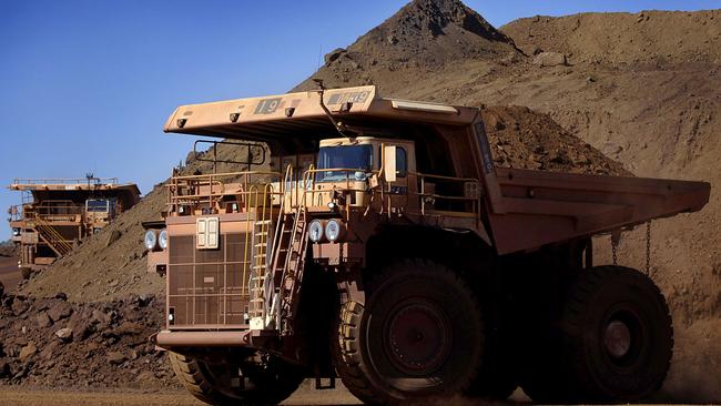 Heavy earth moving trucks at the Tom Price iron ore mine, operated by Rio Tinto Group, are lit up by the afternoon sun in Pilbara, north Western Australia on Wednesday, July 26, 2006. BHP Billiton Ltd., the world's largest mining company, is losing the support of investors and steelmakers for its proposed $128 billion takeover of Rio Tinto Group. Photographer: Jack Atley/Bloomberg News