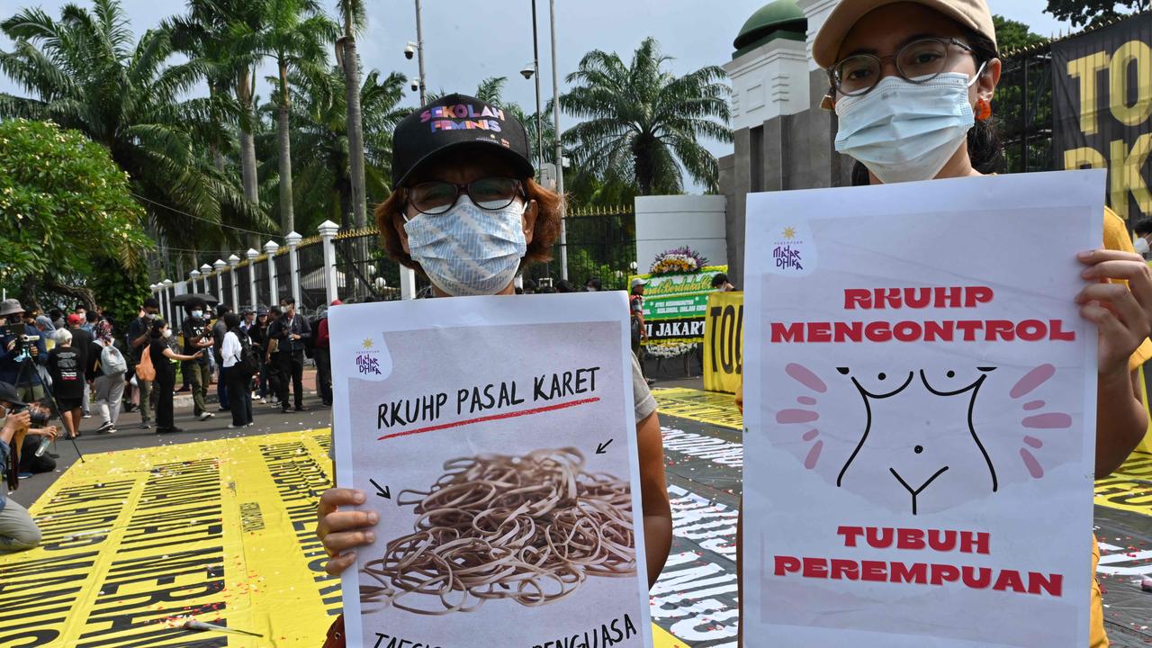 An activist (right) holds a placard that reads: 'The new criminal code controls women's bodies' during a protest against the code outside the parliament building in Jakarta. Picture: Adek Berry / AFP