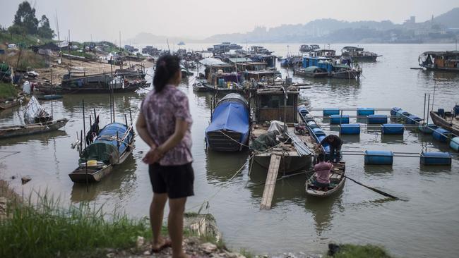 In this picture taken on September 9, 2017, a woman from the Tanka looks at boats moored on a river in Datang, in southern China's Guangdong province. Along southern China's snaking rivers, an ancient fishing community that once lived and worked exclusively on the water has been finding its way to land. Wooden fishing boats, wispy nets and bamboo steering poles exemplify the traditions of the "Tanka" -- the term for generations of rural Chinese who have eked out an aquatic existence. / AFP PHOTO / FRED DUFOUR