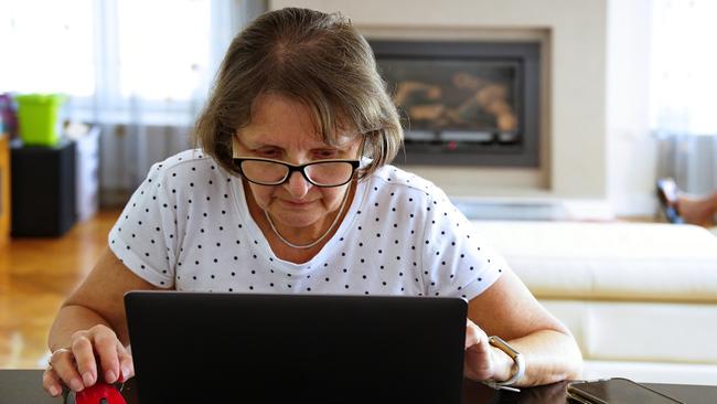 An older woman working on a laptop from home.