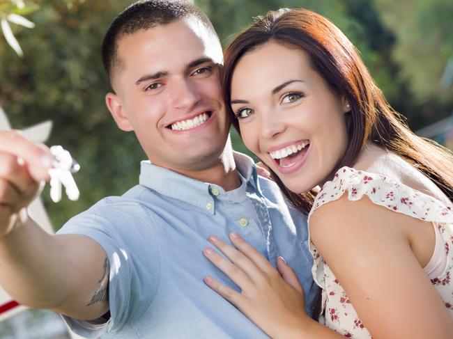 Mixed Race Excited Military Couple with New House Keys and Sold Real Estate Sign Outside.