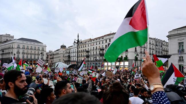 Demonstrators wave Palestinian flags and hold signs as they attend a rally in support of the Palestinian people in Madrid.