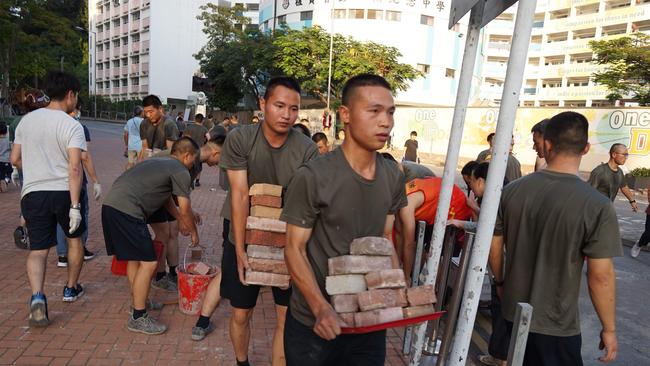 Stark message: Troops from the People's Liberation Army barracks in Hong Kong emerged to help clean up on Saturday. Picture: AFP