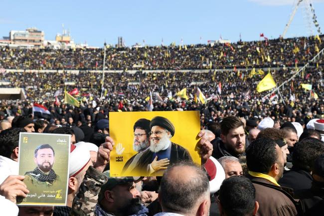 A mourner carries the portraits of Hezbollah's slain leader Hassan Nasrallah and Hashem Safieddine during their funeral