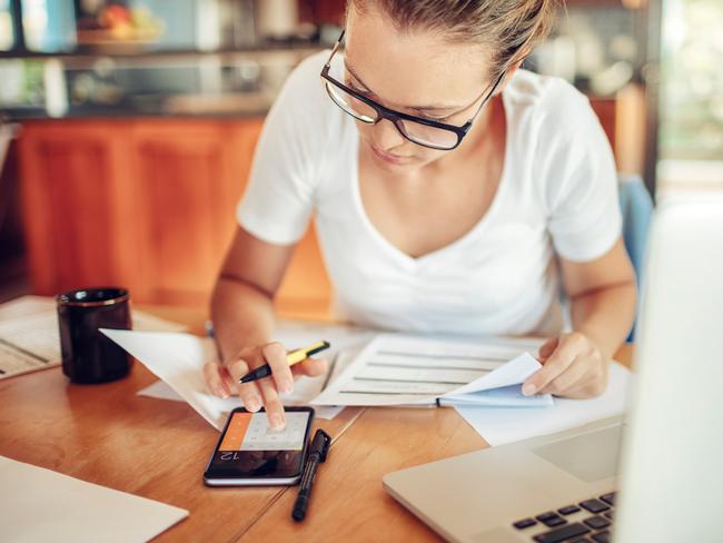 A woman using her phone to add up the cost of her bills including her home loan and energy costs. Picture: iStock.