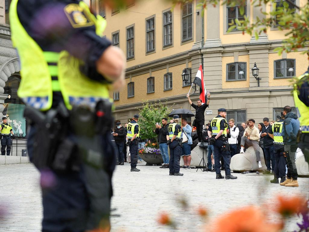 Police stand near protesters burning a Koran in Stockholm. Picture: Oscar Olsson/TT/AFP