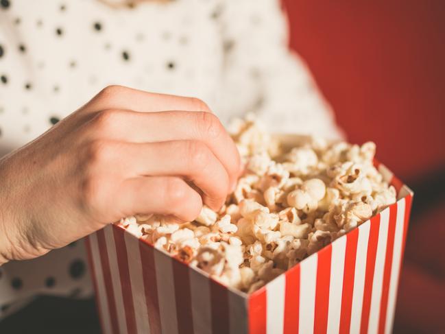 Closeup on a young woman eating popcorn in a movie theater