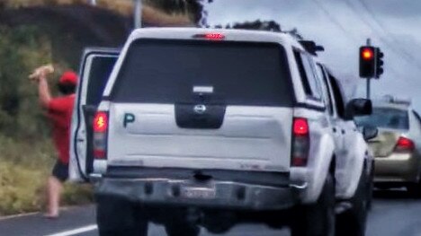 The passenger pegging a glass bottle at the sedan, his mate almost smashed in to, however there is a small car sandwiched between the two cars, unwittingly embroiled in the road rage incident. Picture: Brett Lynch/YouTube