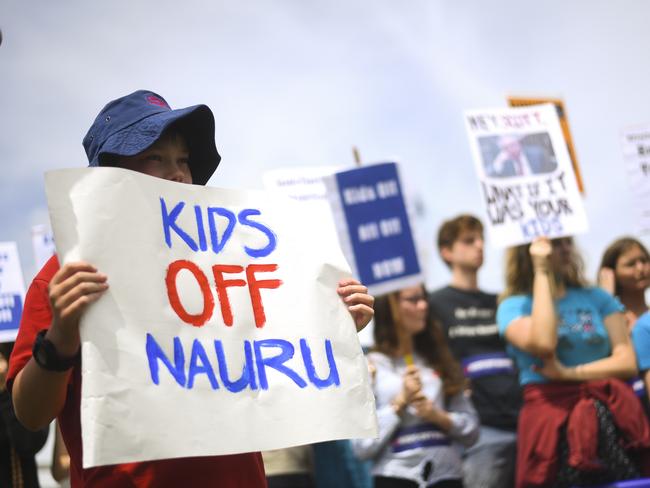 Protesters hold up signs during a rally demanding the resettlement of kids held on Nauru outside Parliament House in Canberra, Tuesday, November 27, 2018. (AAP Image/Lukas Coch) NO ARCHIVING