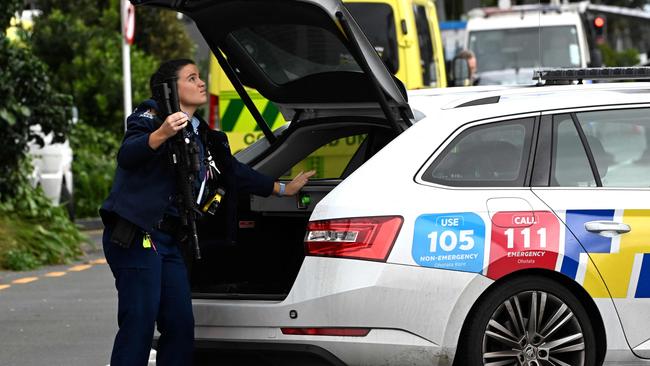 A police officer takes out a gun from her car at site of a shooting in central Auckland. Picture: AFP.