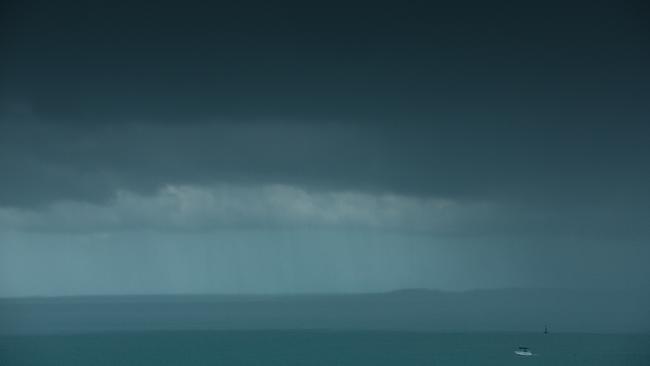 A lone fisho skirts a wall of rain as storms move across Darwin Harbour. Picture GLENN CAMPBELL