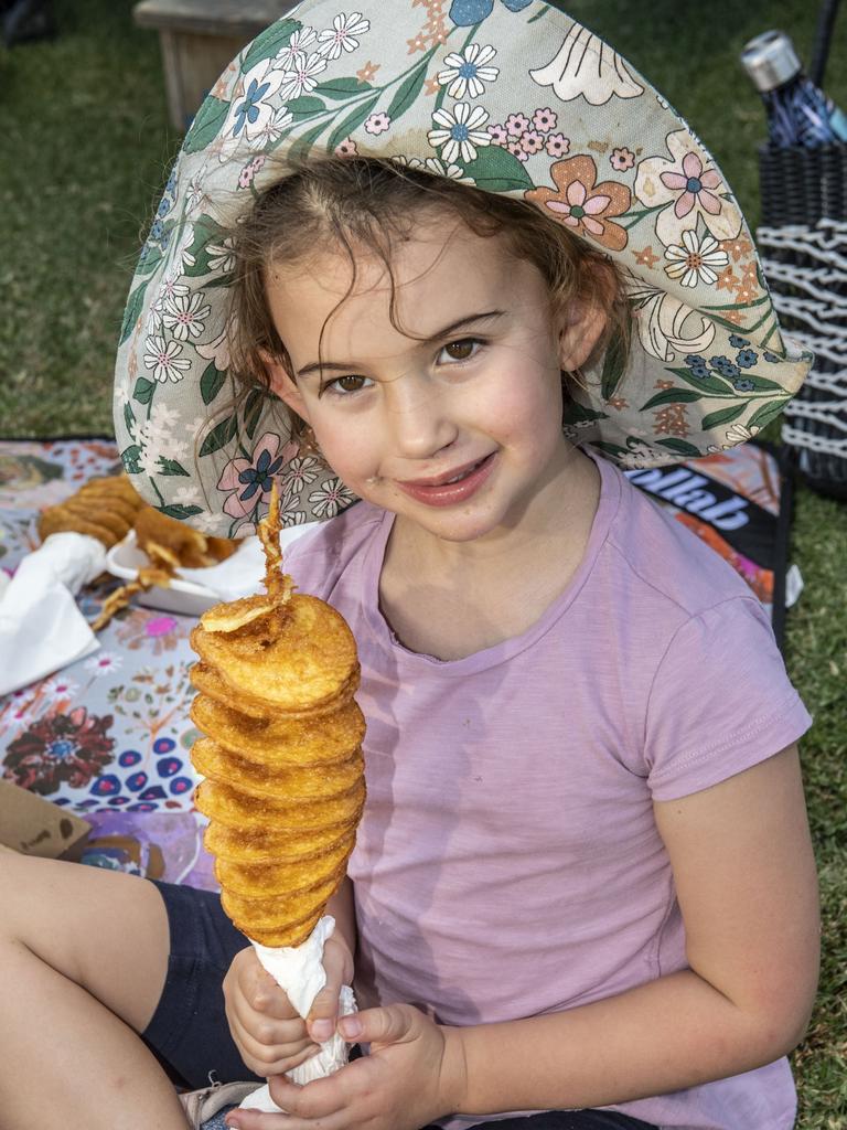 5 year old Olive McColley makes quick work of a twisted potato at the Toowoomba Street Food Festival at Pittsworth. Saturday, January 29, 2022. Picture: Nev Madsen.