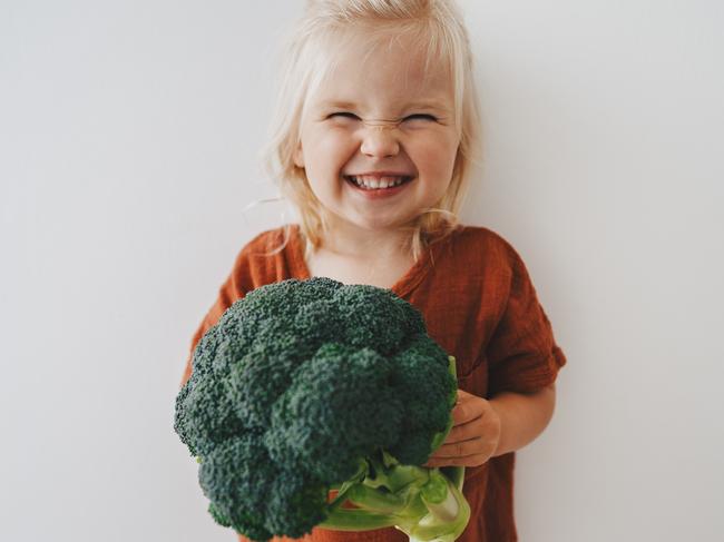 Child girl with broccoli healthy food vegan eating lifestyle organic vegetables plant based diet nutrition funny kid happy smiling