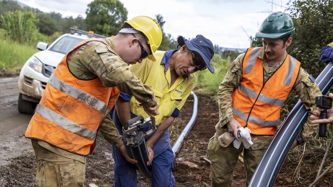 Australian Army soldiers Sapper Brayden Taylor (left) and Sapper Daniel Coleman from the 6th Engineer Support Regiment work with Lismore City Council worker Mr Ian Mackie to restore water to Nimbin, New South Wales.