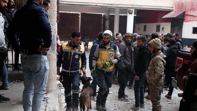 People gather as Syrian White Helmets civil defence members and experts search for potential hidden basements at the Sednaya prison. Picture: AFP.