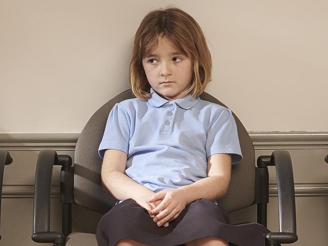 a schoolgirl waits in the naughty chairs outside the head's office.