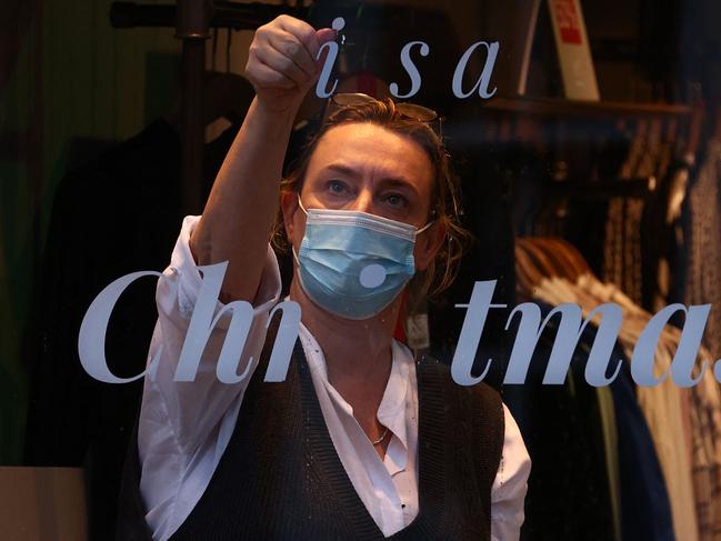 A member of staff scrapes off the Christmas lettering from the window of a store on Christmas Eve in Guildford, south of London. Picture: AFP Photo