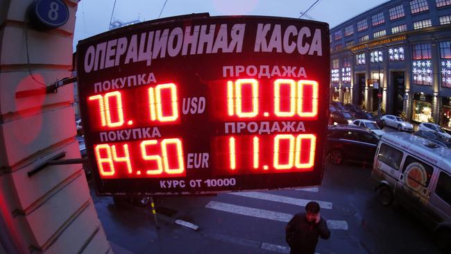 A man stands next to a building under a board showing currency exchange rates in Moscow. Picture: Reuters