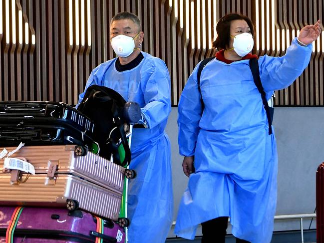 TOPSHOT - International travellers wearing personal protective equipment (PPE) arrive at Melbourne's Tullamarine Airport on November 29, 2021 as Australia records it's first cases of the Omicron variant of Covid-19. (Photo by William WEST / AFP)