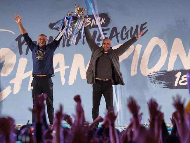 Manchester City's Spanish manager Pep Guardiola (R) and Manchester City's Belgian defender Vincent Kompany (L) show the Premier League trophy to supporters outside the Etihad Stadium in Manchester, northern England on May 12, 2019 - Manchester City held off a titanic challenge from Liverpool to become the first side in a decade to retain the Premier League on Sunday by coming from behind to beat Brighton 4-1 on Sunday. (Photo by Oli SCARFF / AFP)
