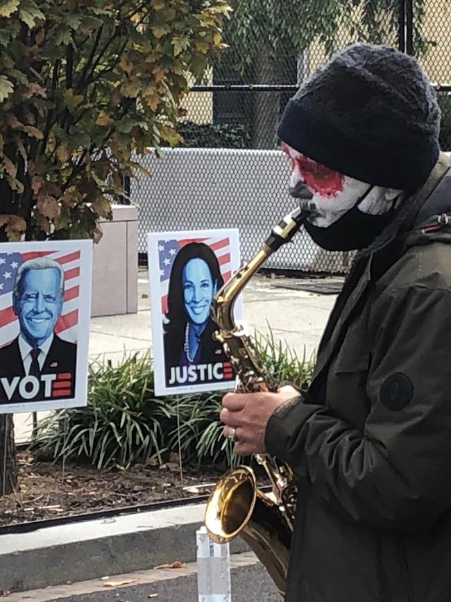 A painted-up saxophonist plays a tune in front of signs urging Americans to vote for Joe Biden and Kamala Harris. Picture: Chris Kenny