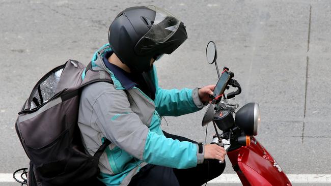 A delivery driver using his mobile phone on his scooter in Brisbane. Picture: AAP/David Clark