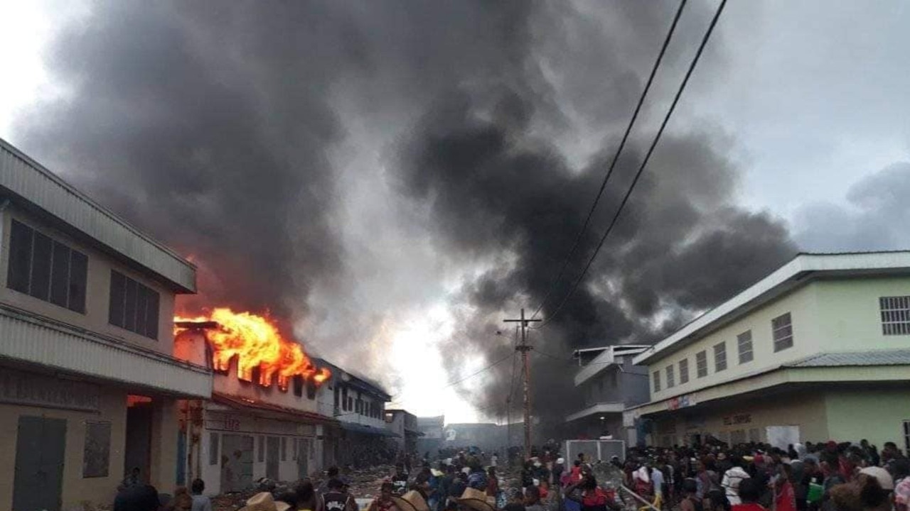 Large crowds are seen as buildings burn in the Solomon Island's capital of Honiara in the Chinatown district, as civil unrests continues. FILE PHOTO