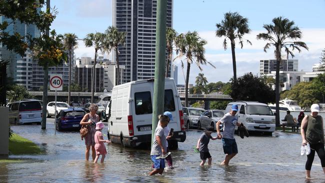 Flooding from the King tide at Budds Beach at Surfers Paradise was made worse by the approaching storm system. People wading through the floodwaters. Picture Glenn Hampson