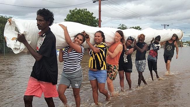 Fitzroy Crossing residents carry the Ngurrara canvas to safety from the flood-threatened Mangkaja Arts Resource Agency. Picture: Andrea Myers / Wangki Radio