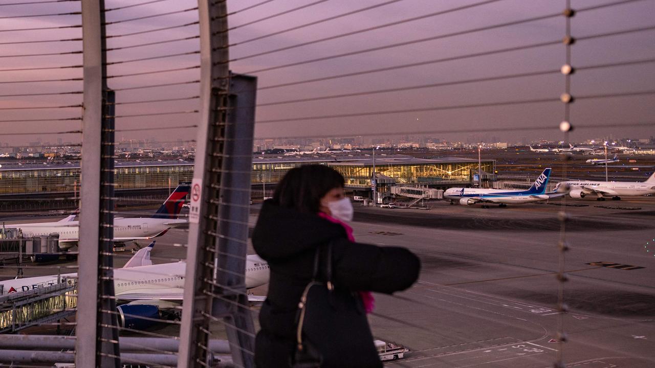 A woman looks on from the observation deck of Tokyo's Haneda international airport as Japan announced plans to bar all new foreign travellers over the Omicron variant of Covid-19.
