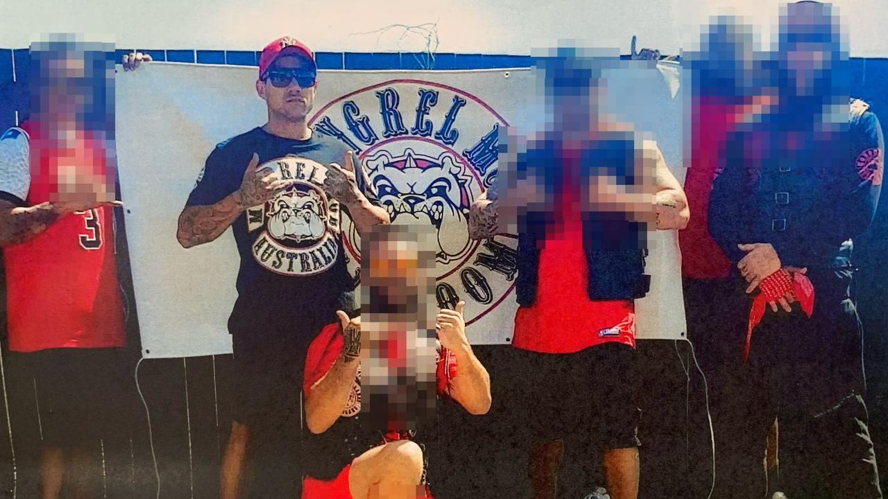 Alleged Mongrel Mob Mackay chapter president Karl Robert Bailey pictured with associates all dressed in red and black in front of a Mongrel Mob banner. Mr Bailey, 30 was arrested as part of a police operation targeting the Mongrel Mob in Mackay.