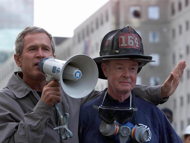 Former US President George W. Bush (L), standing next to retired firefighter Bob Beckwith, as he surveys the damage at the site of the World Trade Centre. Picture: AFP Photo / Paul J. Richards