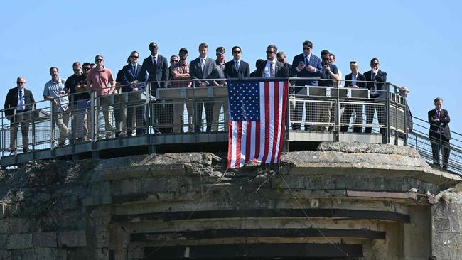 US Secret Service personnel and delegation members stand atop a WWII-era German bunker and former coastal gun-installation draped in a US flag as they attend a speech by the US President in France for D-Day in June. Picture: