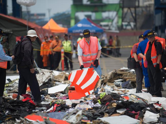 Officials from the US National Transportation Safety Board examine recovered debris from the ill-fated Lion Air flight. Picture: AFP