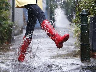 Model splashing about in rain, wearing red gumboots